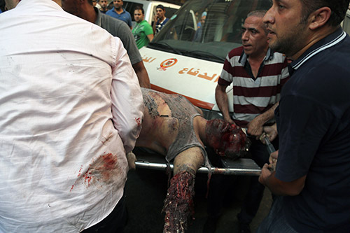 Men carry the corpse of a civilian who was killed in the Roweis explosion