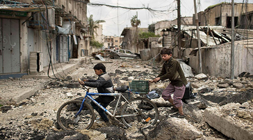 Iraqi boys walk on a destroyed street in a neighborhood recently retaken by Iraqi security forces during fighting against Daesh in Mosul